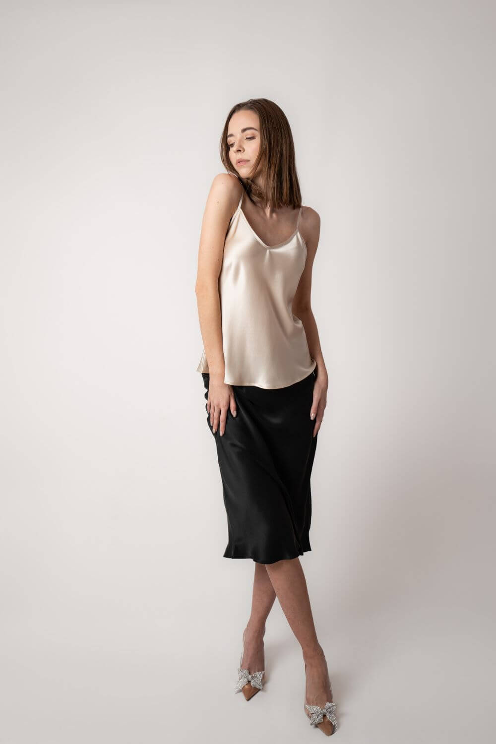 Model wearing Silk Closet Champagne Camisole top and black skirt in studio