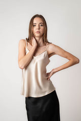 Woman wearing silk champagne camisole and black skirt in studio