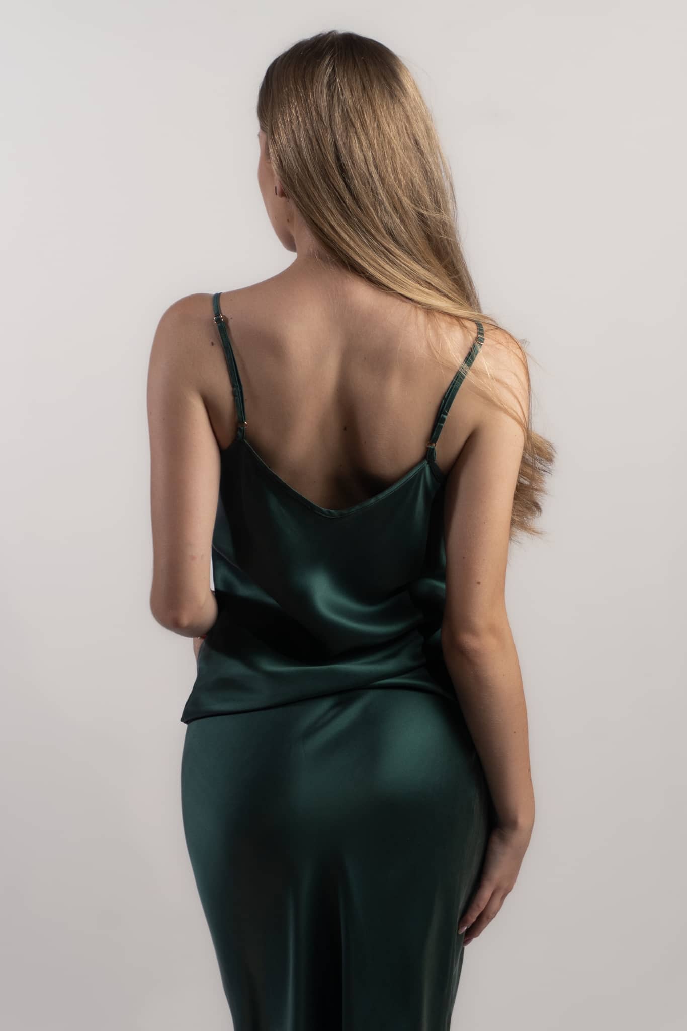 Woman wearing silk closet green skirt and camisole top back view. Luxury silk