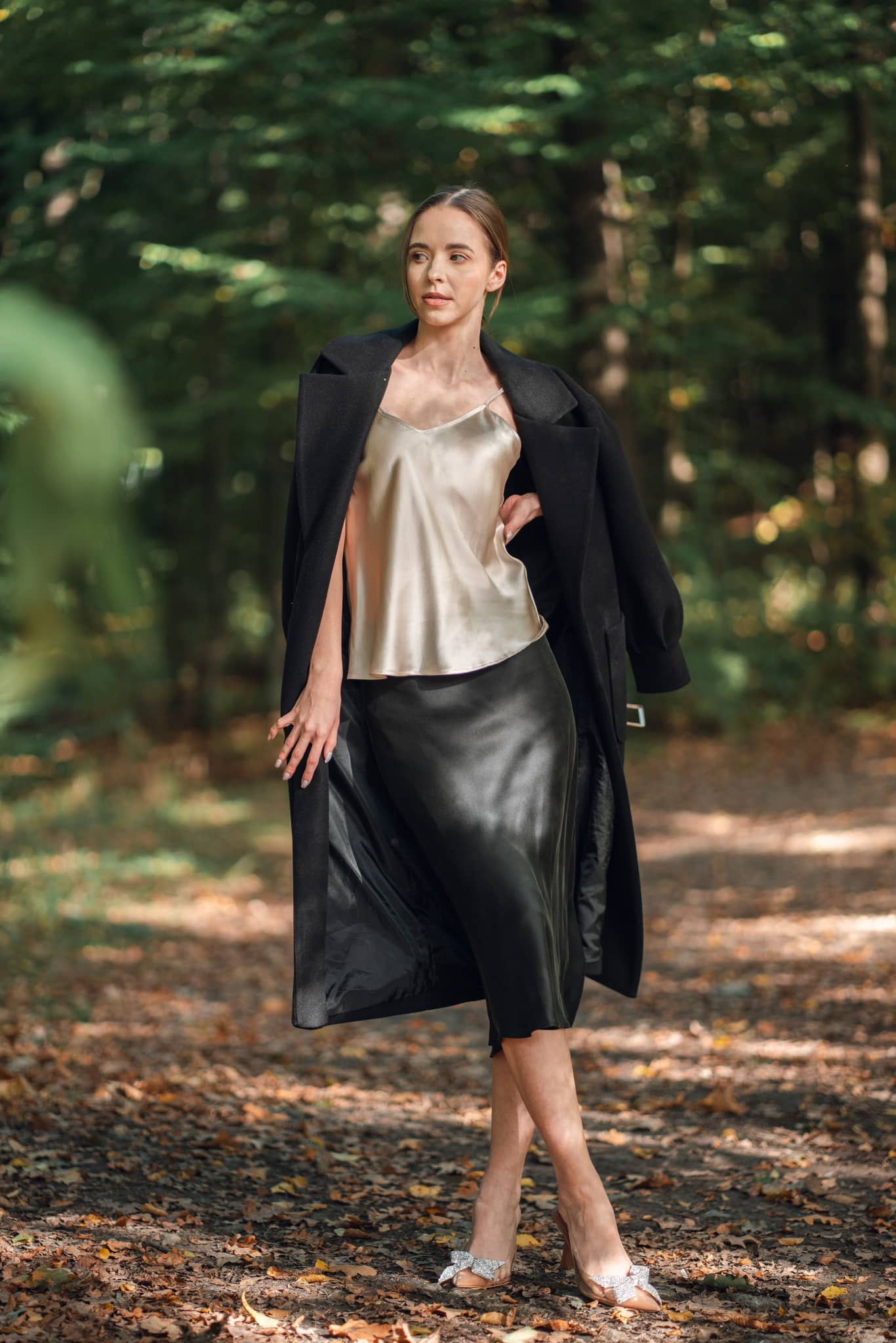 Woman wearing champagne camisole and black skirt in woods