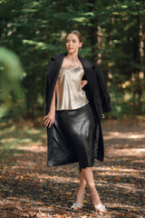 Woman wearing champagne camisole and black skirt in woods