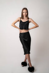 Model wearing Silk Closet black midi skirt and black crop blouse in studio