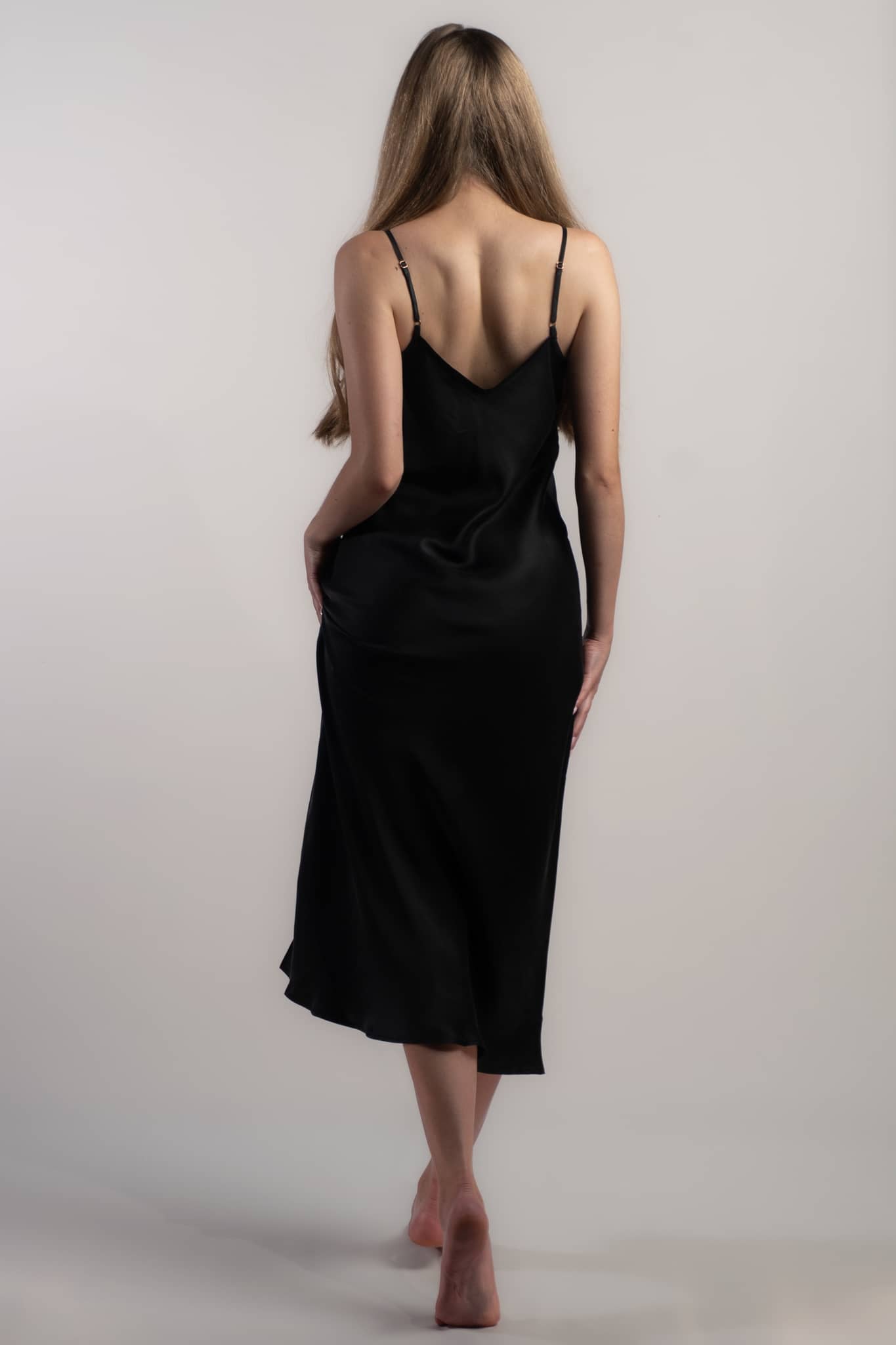 Woman wearing black silk closet classic slip dress back view