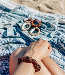 Silk Closet silk Angelina brown hair midi scrunchie.  Gentle hold for healthy hair.  On wrist at the beach.