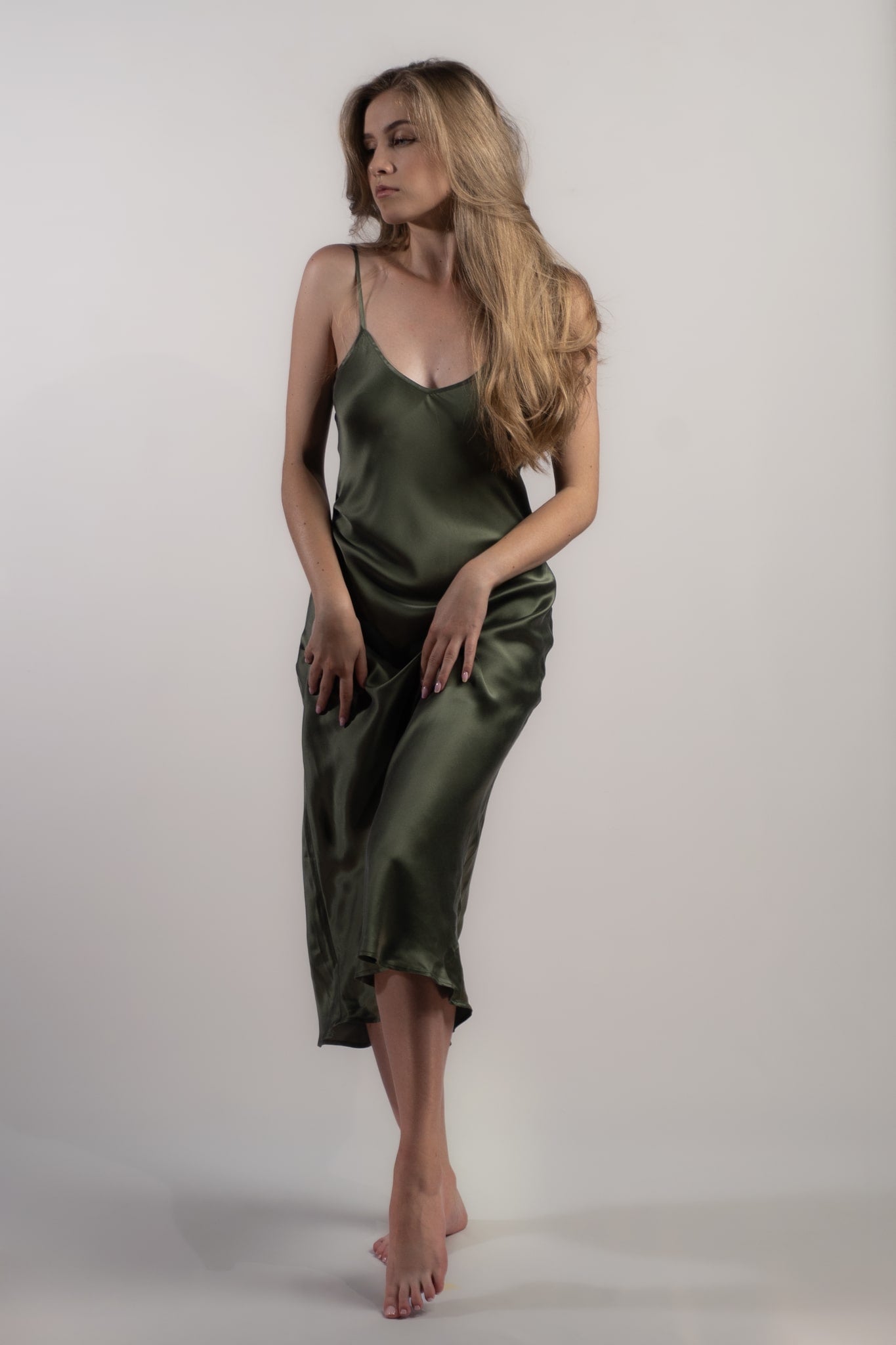 Woman wearing Silk Closet silk slip dress in olive green. 100% pure sandwashed silk with bias cut and adjustable spaghetti straps.
