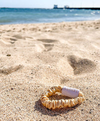 Silk Closet gold hair scrunchie. Silk for gentleness on hair. At beach.