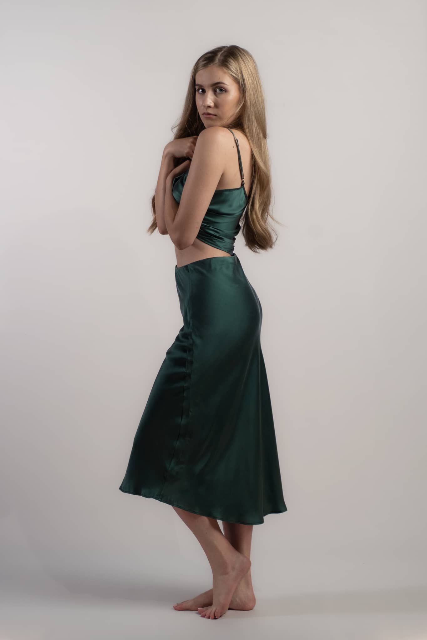 Woman wearing silk closet green skirt and camisole top. Side view