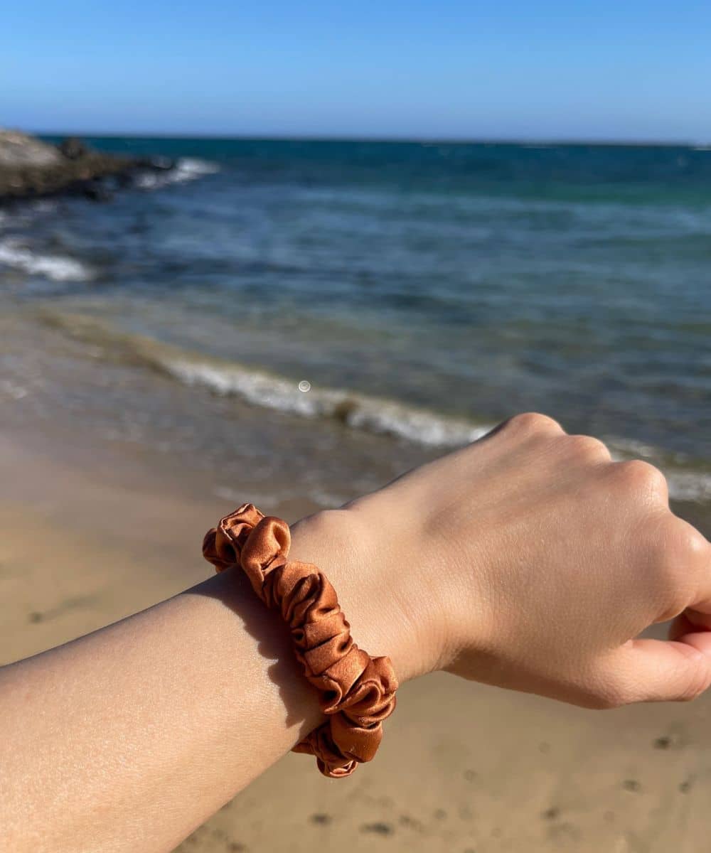 Orange russet silk hair scrunchie in midi size on wrist