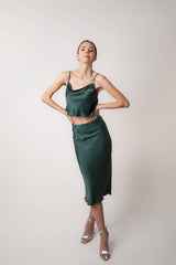 Woman wearing silk closet green skirt and camisole top in studio. Party outfit