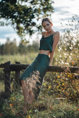 Woman sitting on couch wearing Silk Closet cowl neck sandwash silk green crop top and skirt outdoors