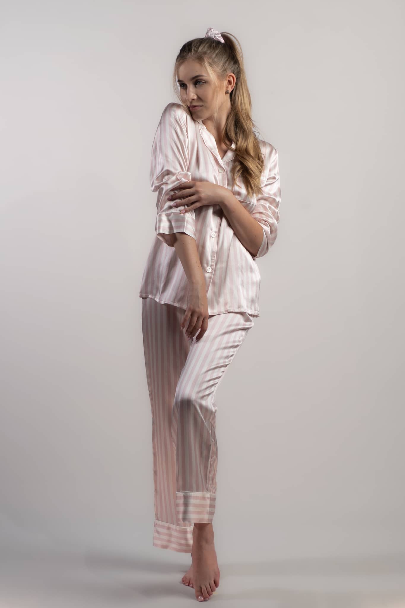 Woman wearing silk closet pink and white striped long pyjama set pants front view.