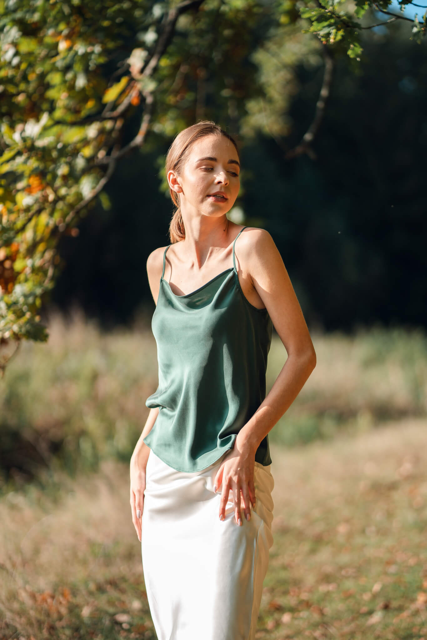 Woman wearing Silk Closet green camisole and ivory silk slip skirt outdoors.