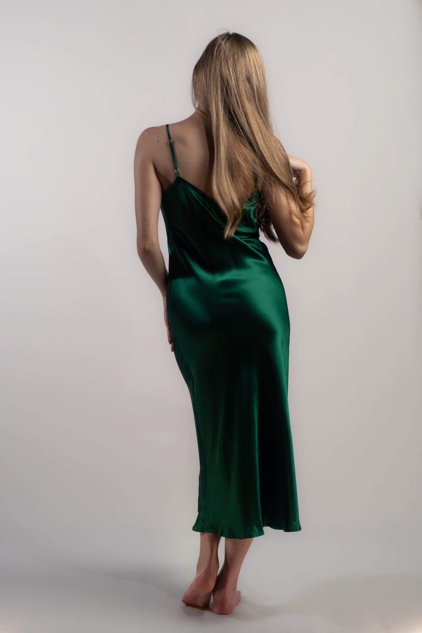 Woman wearing Silk Closet emerald green silk slip dress.  100% pure silk dress with bias cut and adjustable spaghetti straps.  Back view.