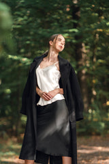 Woman wearing Silk Closet ivory silk camisole and black silk skirt in woods with black jacket