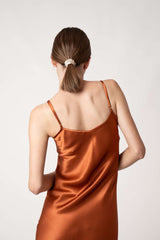 Woman wearing orange silk Closet classic dress back view with scrunchie