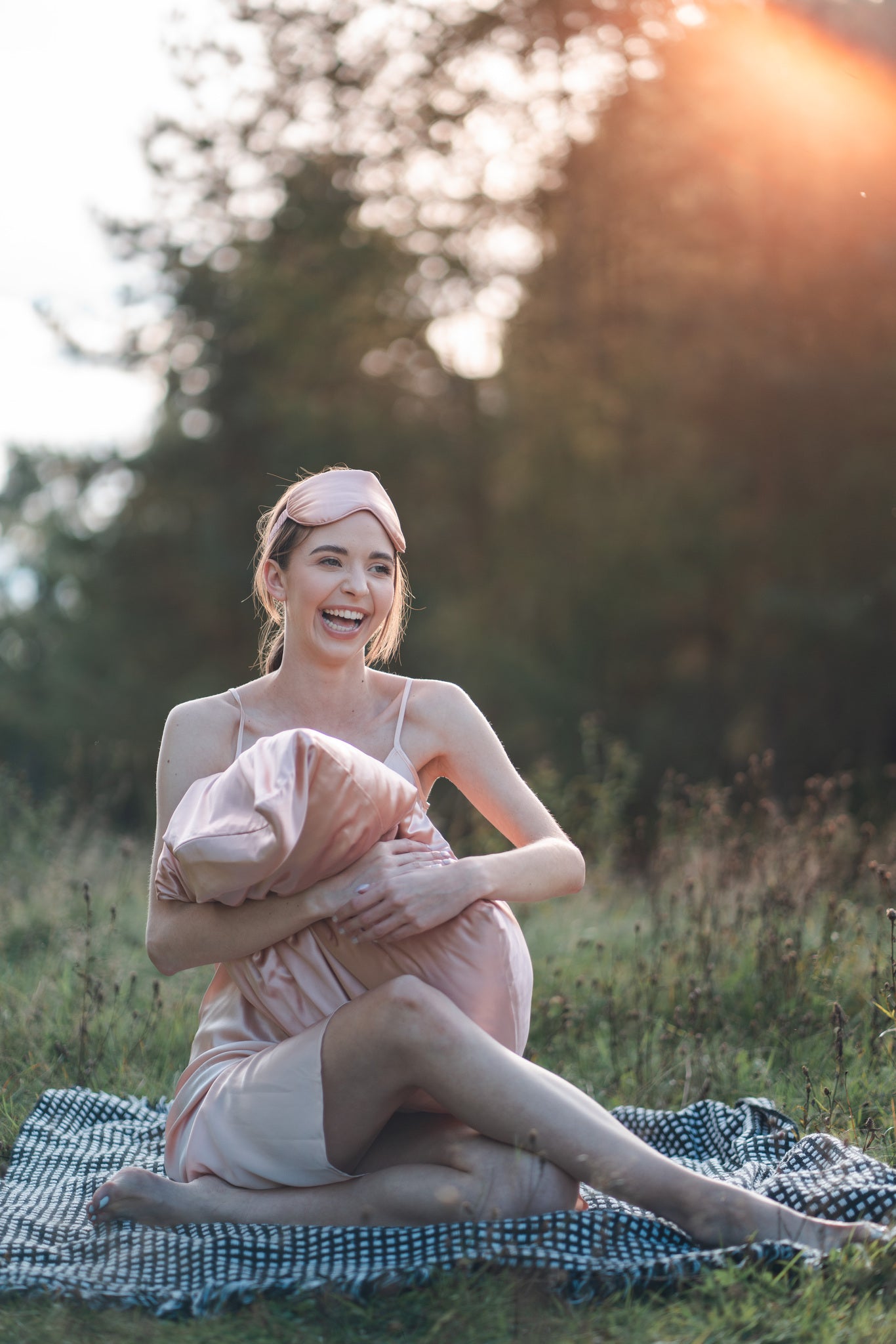 Model wearing pink silk dress outside with silk eye mask and pillowcase