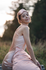 Model wearing pink silk dress outside with silk eye mask and pillowcase