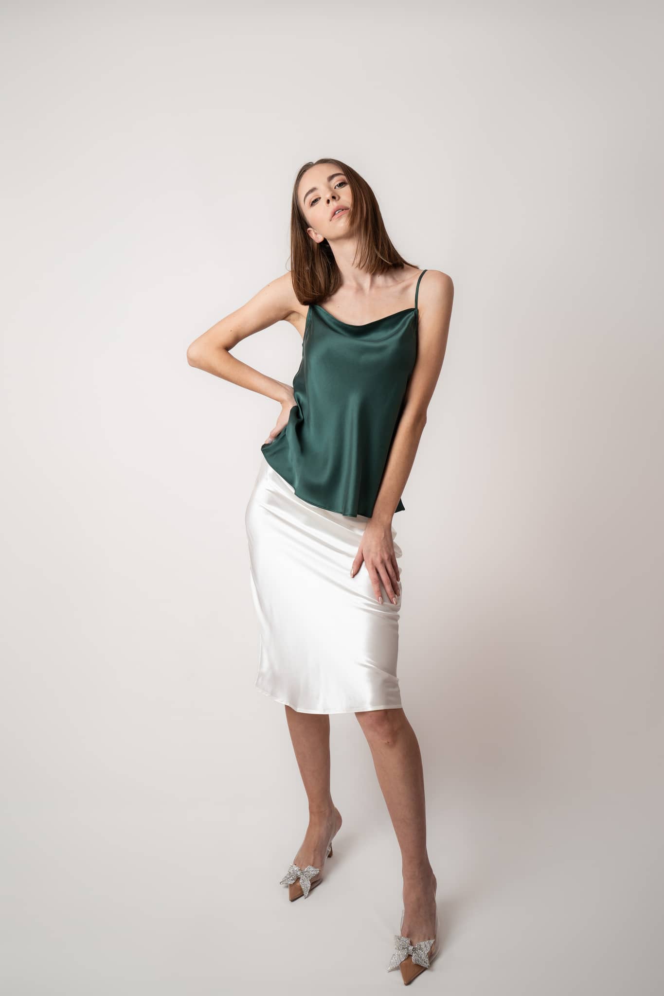 Woman wearing Silk Closet green camisole and ivory silk slip skirt. Studio view.