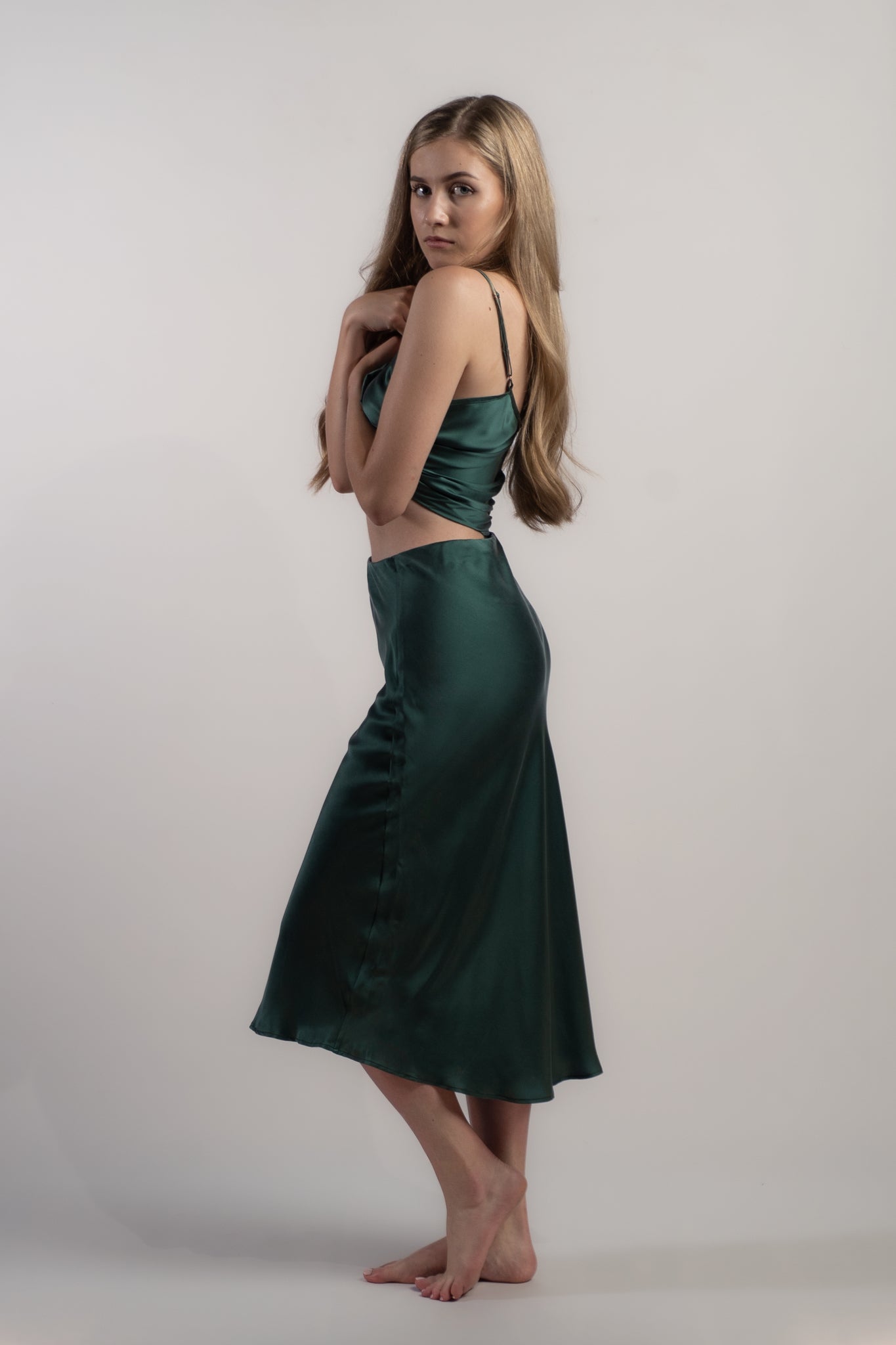 Woman wearing silk closet green skirt and camisole top side view